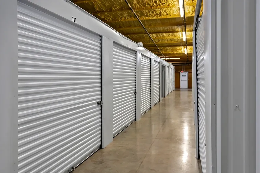 Climate-controlled storage hallway with white roll-up doors and polished concrete floors